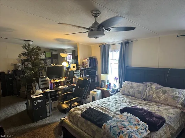 Bedroom featuring dark carpet, ceiling fan, crown molding, and a textured ceiling