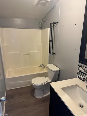 Full bathroom featuring toilet, vanity, tasteful backsplash, bathing tub / shower combination, and hardwood / wood-style flooring