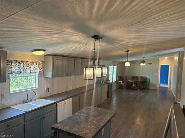 Kitchen with gray cabinetry, dishwasher, dark hardwood / wood-style flooring, and sink