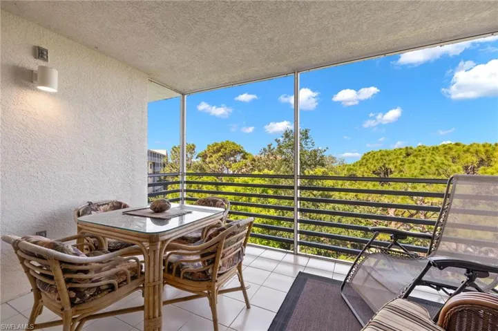 Screened balcony featuring white tile flooring and textured walls