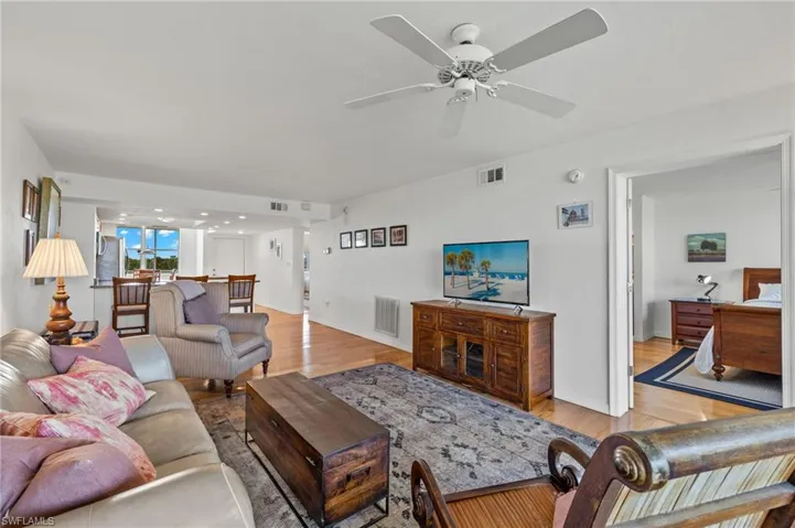 Living area featuring wood-finish flooring, a ceiling fan, and white walls