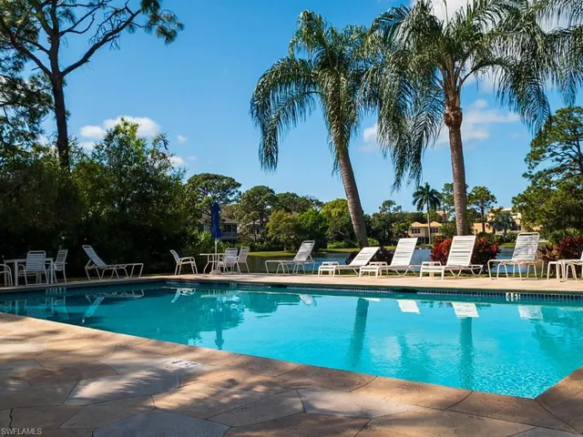 Swimming pool with a flagstone deck, surrounded by mature palm trees and lush landscaping