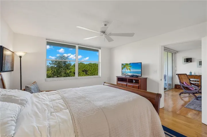 Bright room featuring a large window, a ceiling fan, and light wood-finish flooring