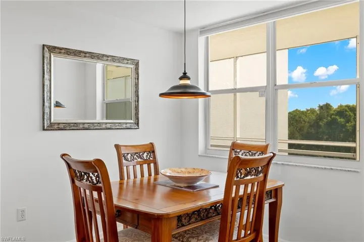 Bright interior with large window, pendant lighting, and a decorative wall mirror