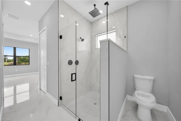 Bathroom with marble tiled flooring, a marble finish shower, and recessed lighting