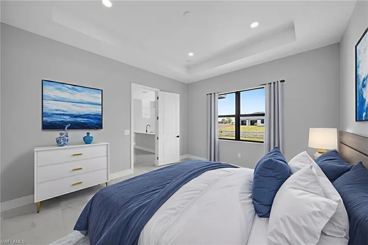 Bedroom featuring a tray ceiling, marble look tile flooring, and recessed lighting