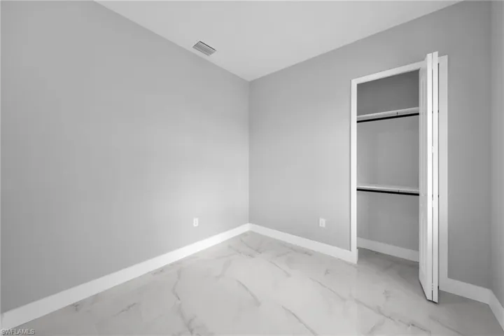 Unfurnished bedroom featuring light marble finish floors and a closet