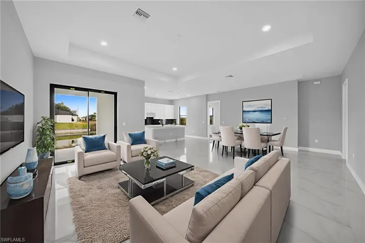 Living room with a tray ceiling, recessed lighting, and light marble finish floors