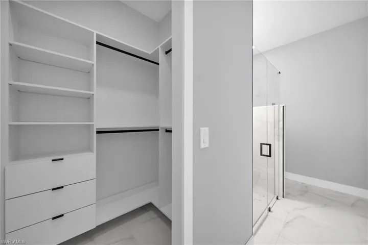 Walk in closet featuring light marble finish floors