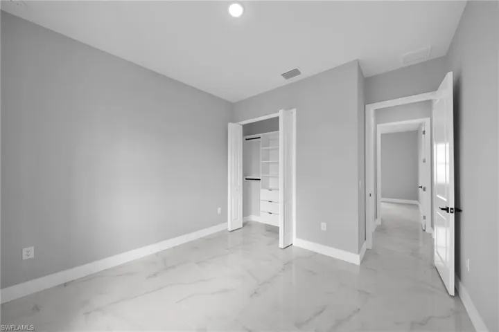 Unfurnished bedroom with a closet and light marble finish floors