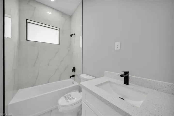 Full bathroom featuring vanity and a combined bath / shower with marble appearance