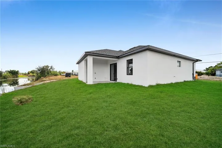 Rear view of property featuring a lawn, a patio area, and stucco siding