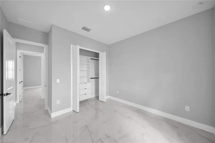 Unfurnished bedroom featuring light marble finish floors and a closet