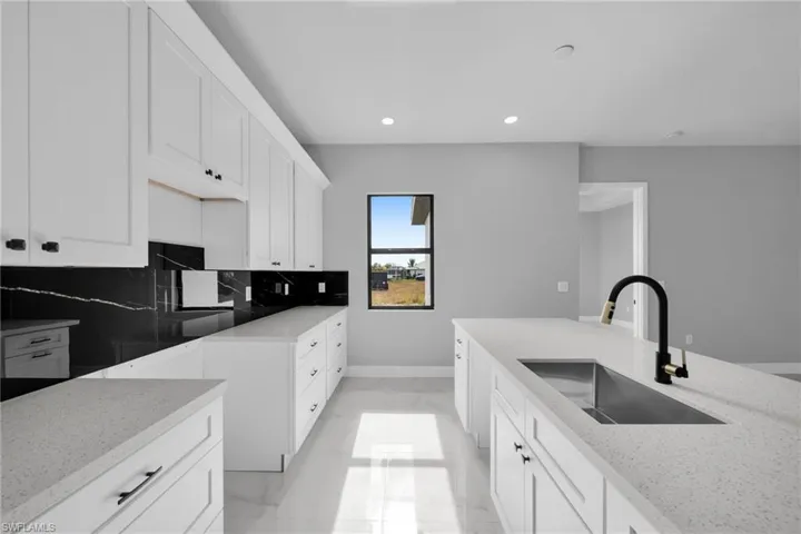Kitchen with white cabinets, light stone countertops, recessed lighting, light marble finish floors, and tasteful backsplash