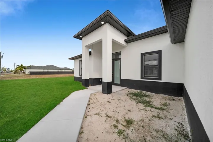Doorway to property with a lawn and stucco siding