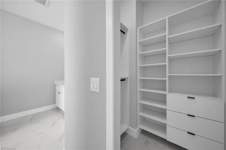 Walk in closet with light marble finish floors