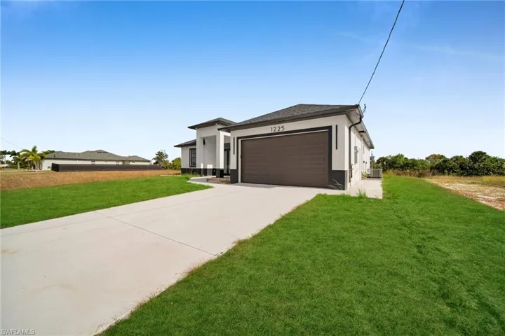 Prairie-style house featuring a front lawn, concrete driveway, stucco siding, and a garage