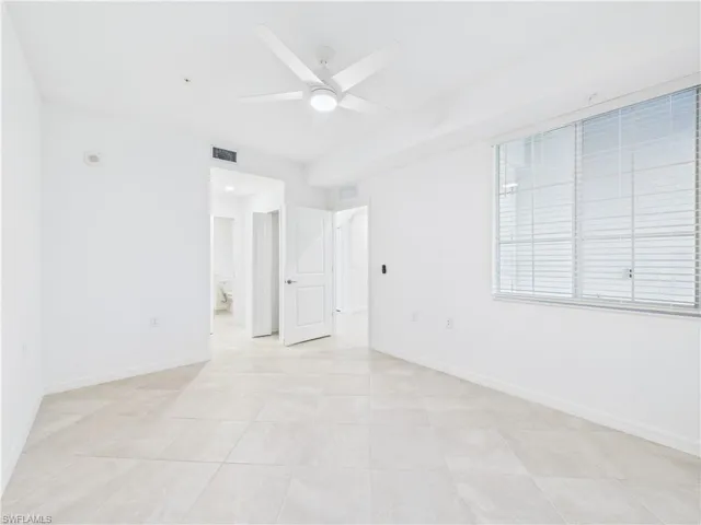 Empty room featuring a ceiling fan and light tile patterned floors