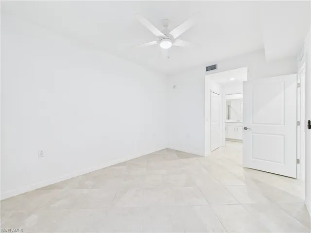 Empty room with a ceiling fan and light tile patterned floors