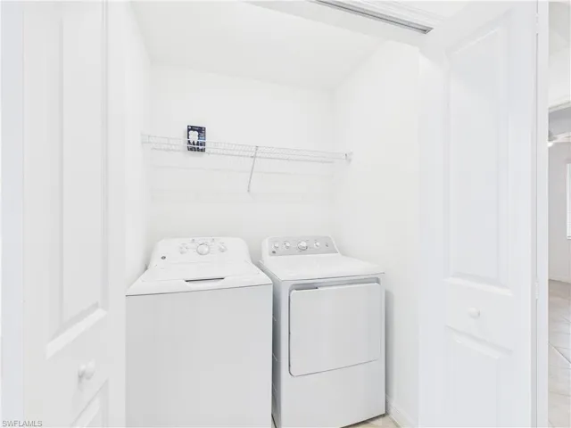 Washroom with washing machine and clothes dryer and baseboards