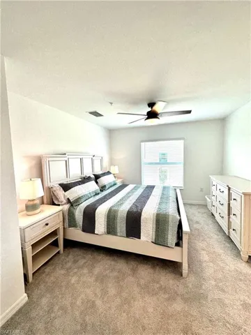 Bedroom with a textured ceiling, carpet, and ceiling fan