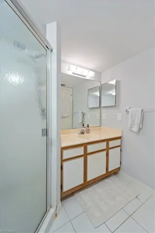Full bath with vanity, a shower stall, and tile patterned flooring