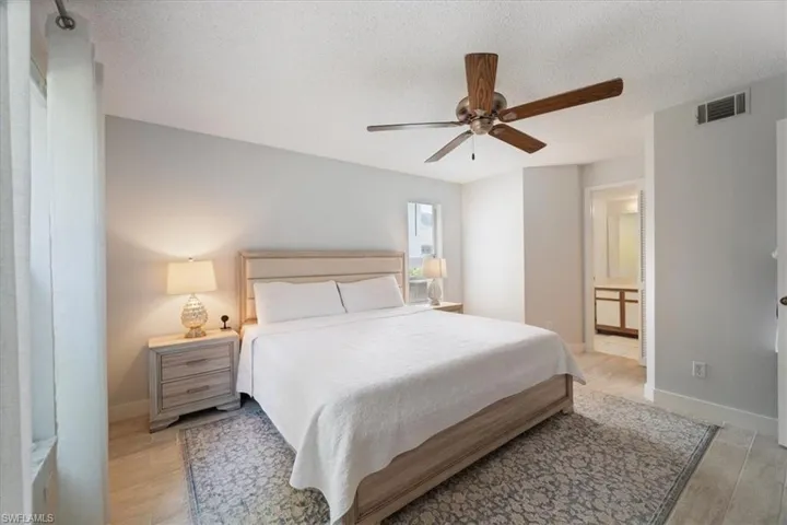 Bedroom with light wood finished floors, a textured ceiling, a ceiling fan, and ensuite bathroom