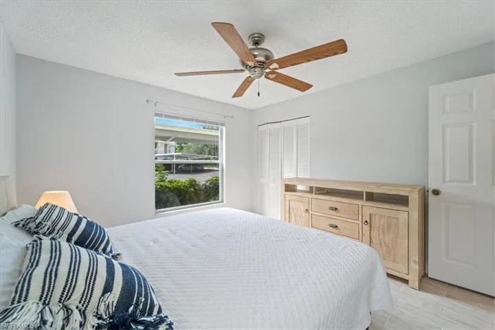 Bedroom with light wood finished floors, a ceiling fan, and a textured ceiling
