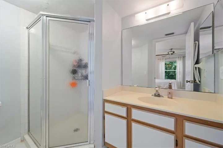 Bathroom with a stall shower, vanity, connected bathroom, and a ceiling fan
