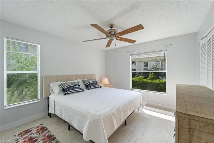 Bedroom with wood finished floors, a ceiling fan, a textured ceiling, and a closet