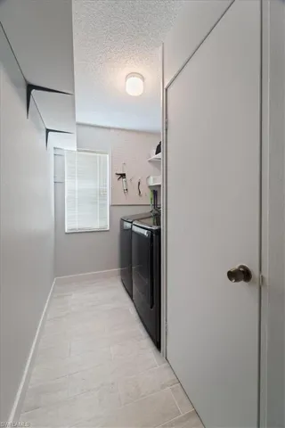 Washroom featuring independent washer and dryer and a textured ceiling