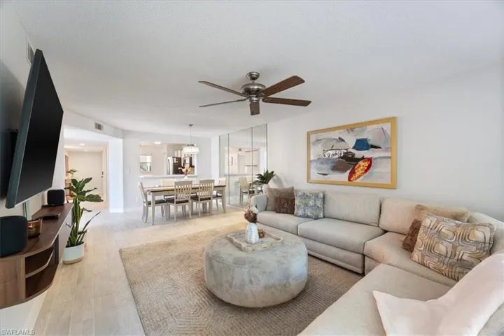 Living room with ceiling fan, light wood-style flooring, a chandelier, and a textured ceiling