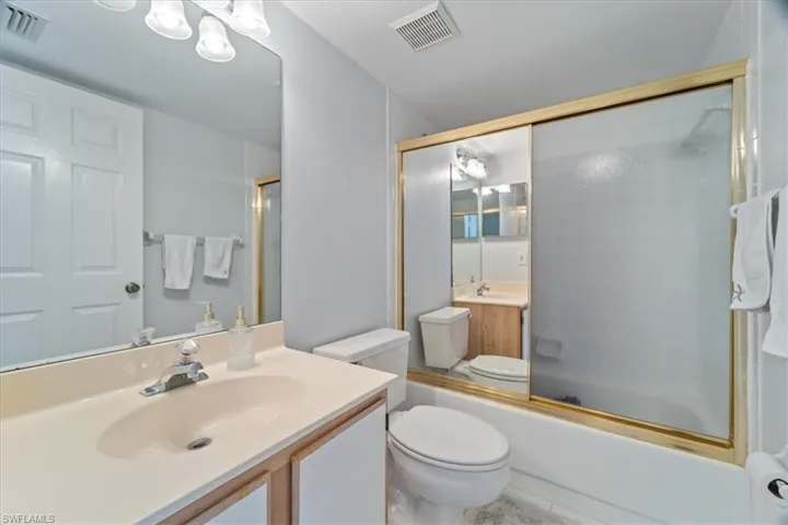 Bathroom with combined bath / shower with glass door and vanity