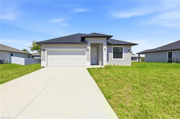 Prairie-style house with an attached garage, driveway, stucco siding, and a shingled roof