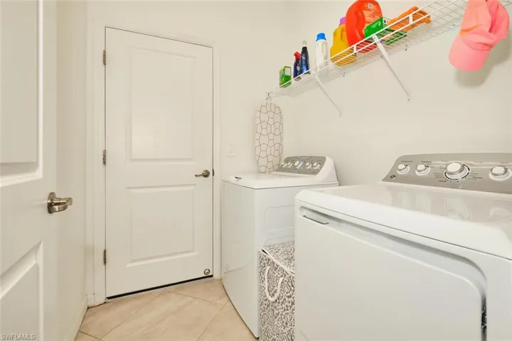 Laundry area with light tile patterned floors and washing machine and clothes dryer