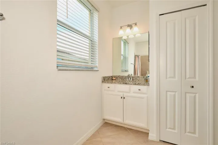 First floor Full bath featuring a closet, vanity, light tile patterned flooring, and a tub/shower with shower curtain