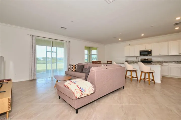 Living area with ornamental molding, light tile patterned flooring, and recessed lighting