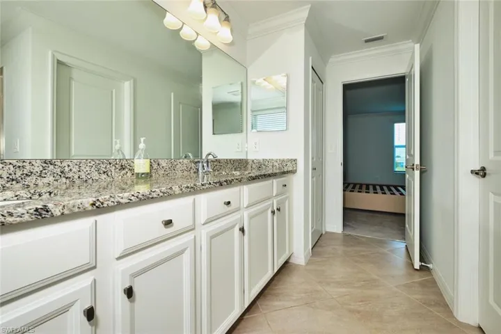 Bathroom with vanity, ornamental molding, ensuite bath, and light tile patterned floors