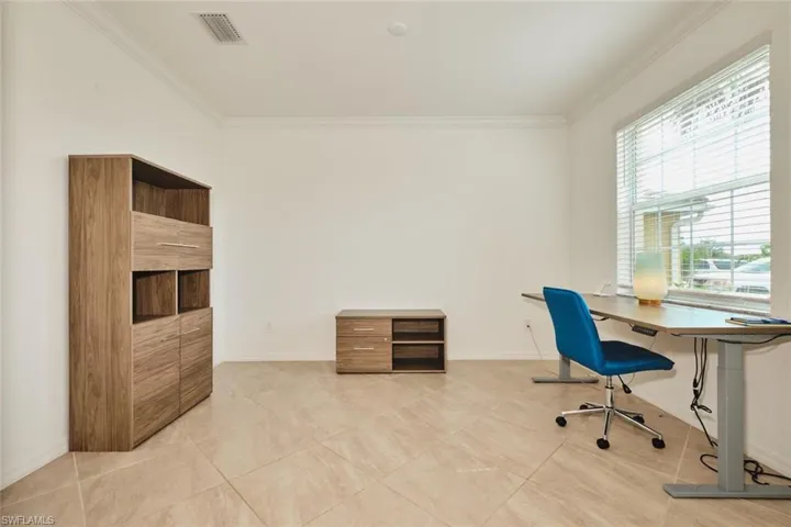 Office area with crown molding and light tile patterned floors