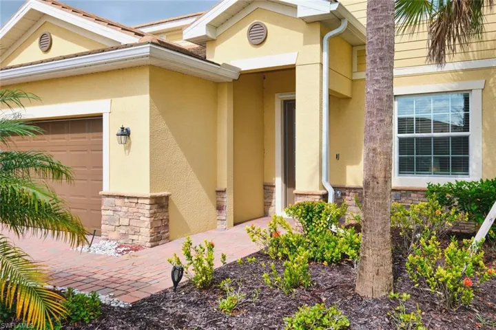 Doorway to property featuring stone siding, a garage, and stucco siding