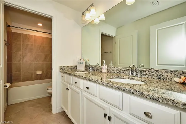 Full bathroom featuring double vanity, light tile patterned floors, tub / shower combination, and recessed lighting