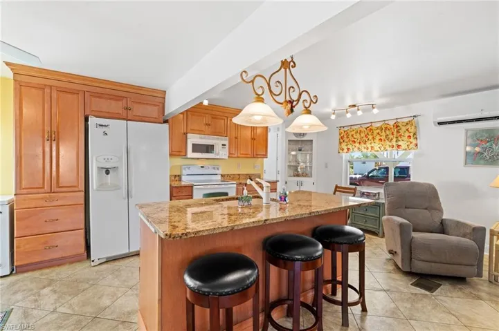 Kitchen with granite countertops, decorative light fixtures, white appliances, and a beautiful center island