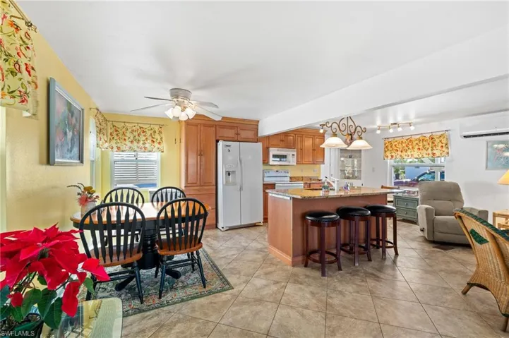 Kitchen and dining view with ceiling fan, hanging light fixtures, a kitchen breakfast bar, and white appliances