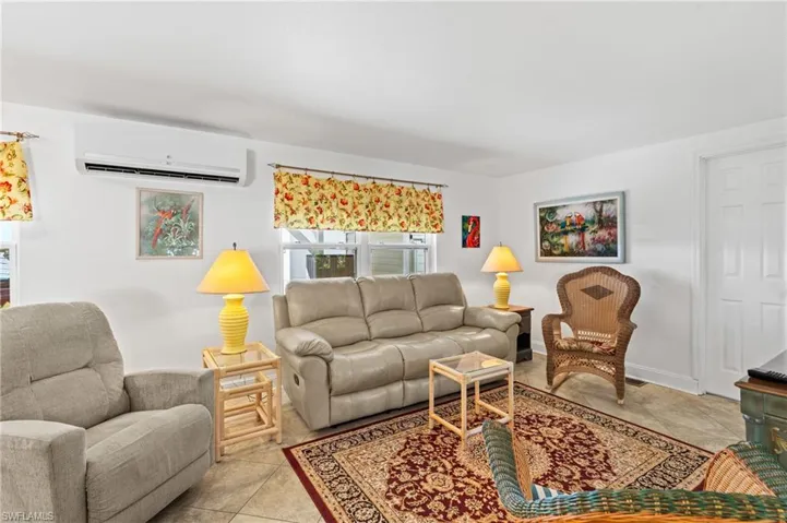 Living room with a wall mounted mini-split AC and light tile patterned floors