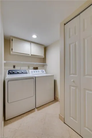 Laundry area with washer and clothes dryer, light tile patterned floors, recessed lighting, and cabinet space