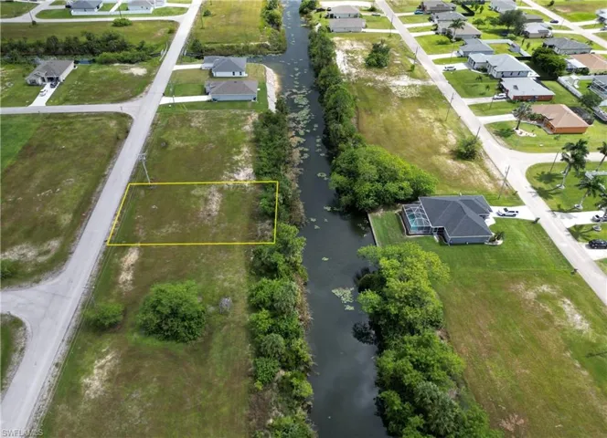 Aerial view of residential area with a large body of water and property parcel outlined