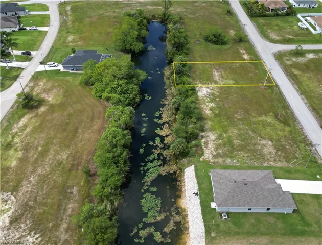 Aerial view of residential area with a large body of water and property boundaries highlighted
