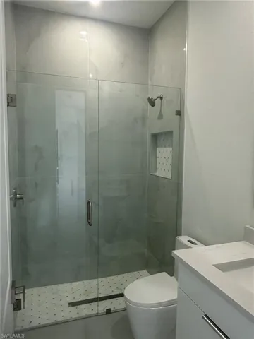 Bathroom featuring vanity, a shower with shower door, and toilet