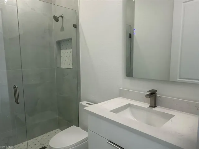 Bathroom featuring vanity, an enclosed shower, and toilet
