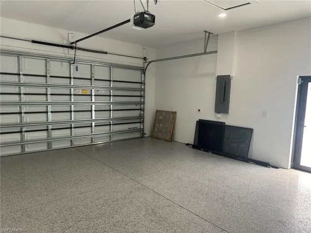 Garage featuring a garage door opener and electric panel